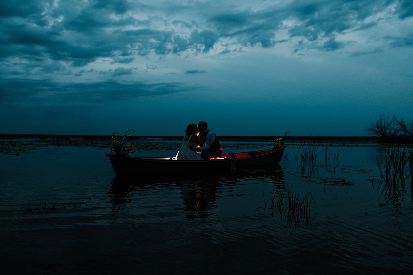 Groom embraces bride in canoe during wedding reception photo by Fedora Media.jpg