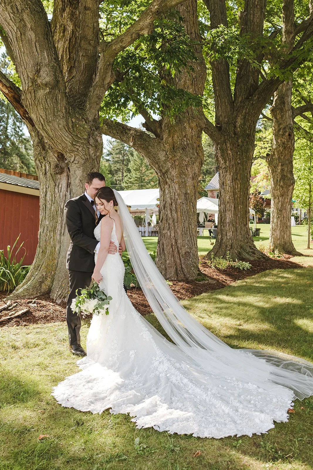 Bride and Groom Embrace with Wedding Dress Train  Fedora Media  Backyard Wedding.jpg