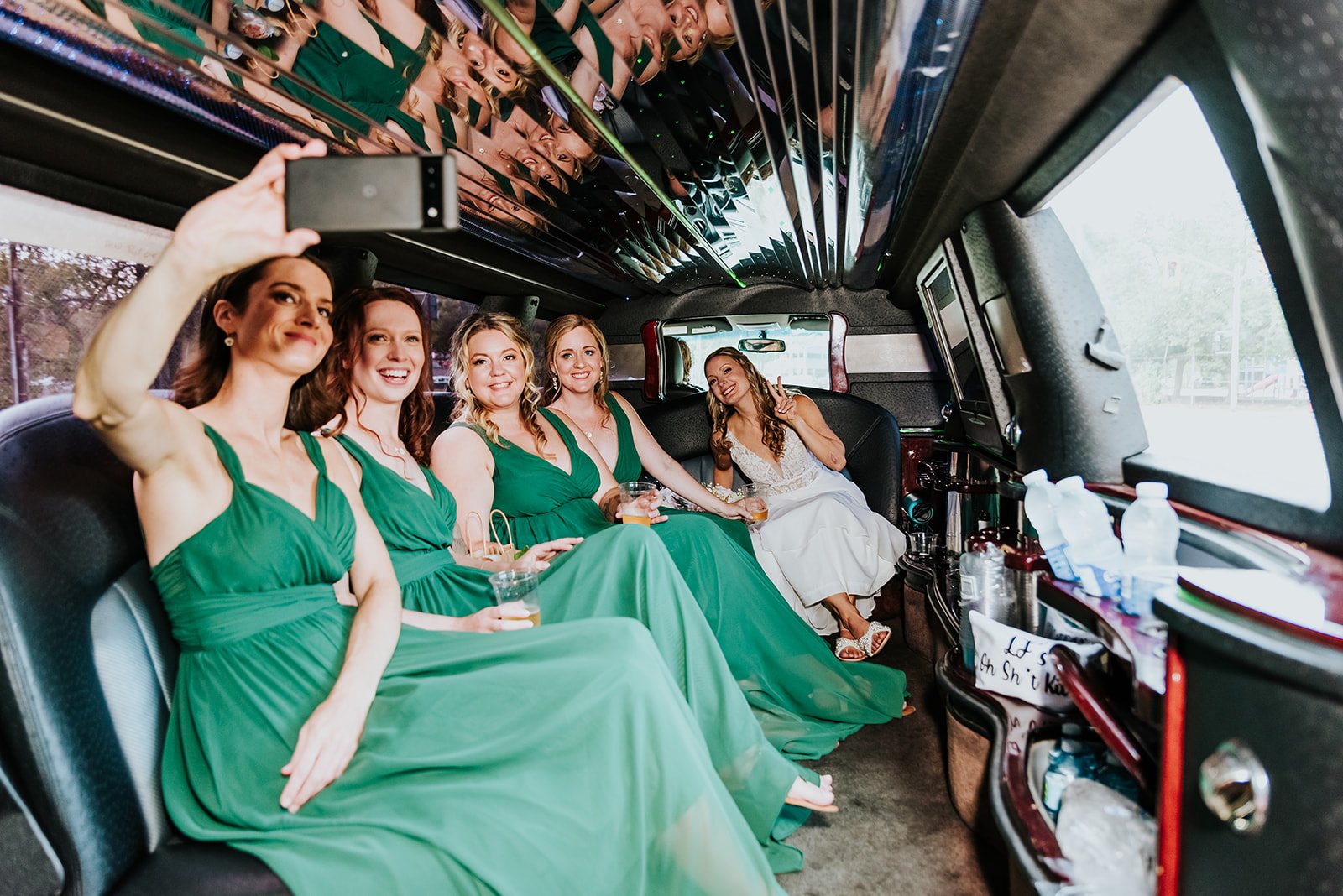 Bride with bridesmaids in green dresses pose in limo photo by Fedora Media.jpg