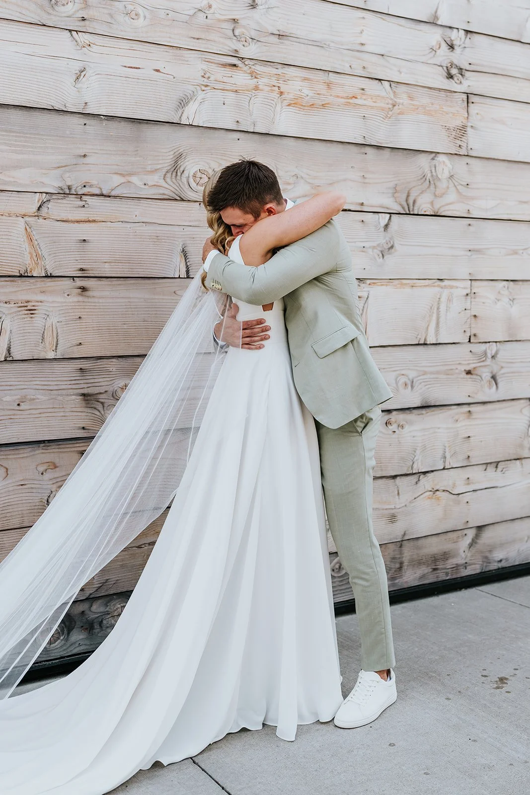Bride and groom hug in front of a wood wall photo by Fedora Media.jpg