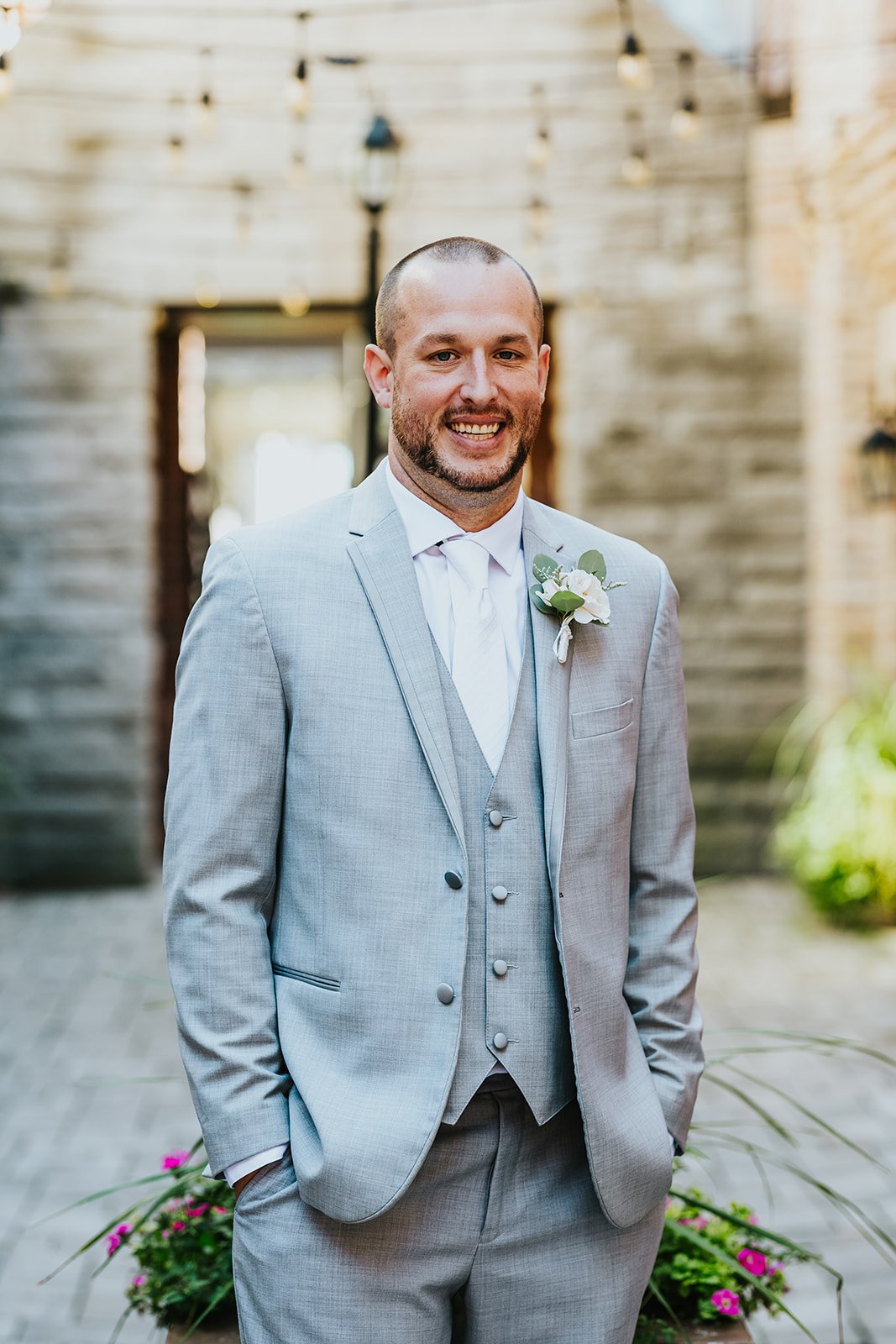 Groom in grey suit and white tie poses at Village square in Burlington photo by Fedora Media.jpg