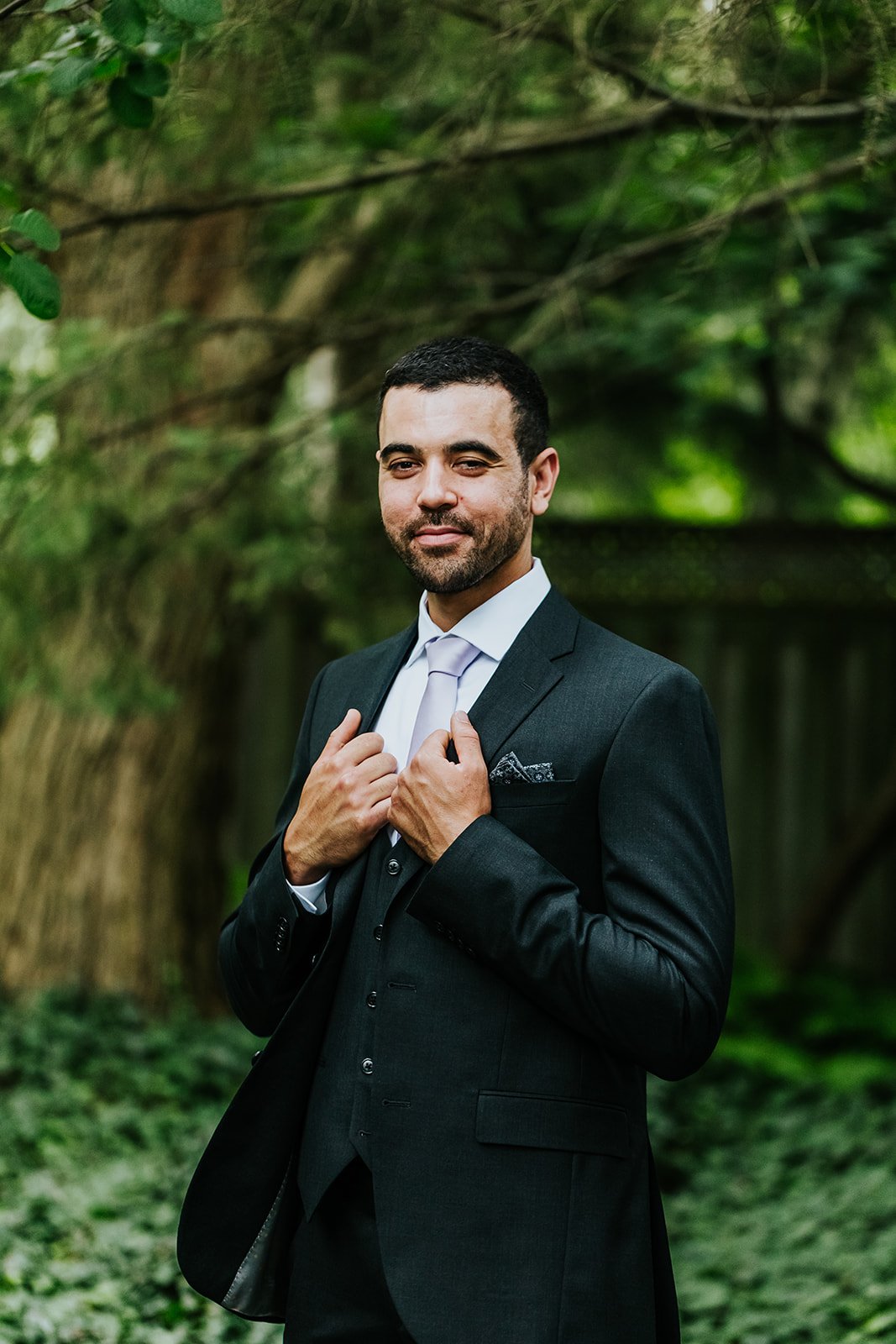 Groom posing in a suit in the garden at backyard wedding photo by Fedora Media.jpg