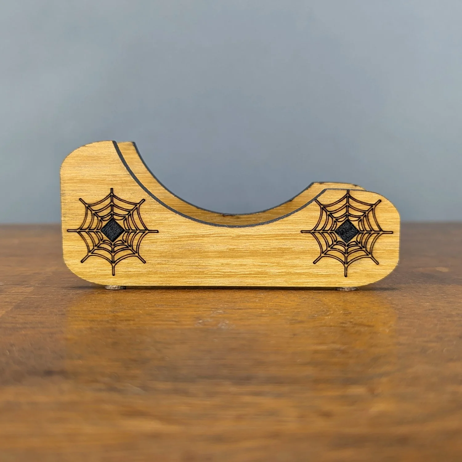 Front view of wooden Webworks Coaster Holder with engraved spiderwebs on each side