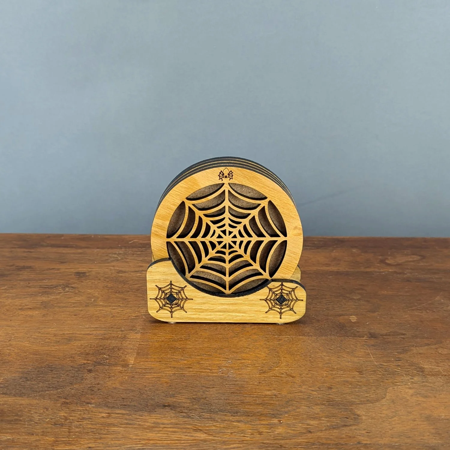 Phantom Web Coaster displayed in wooden Webworks Coaster Holder with spiderweb engravings