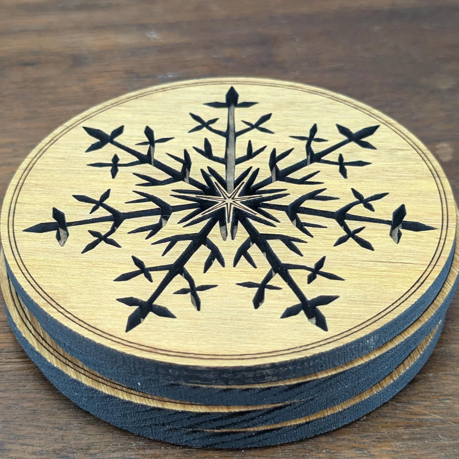 Close-up image of a Black Locust wooden coaster showing detailed laser-cut snowflake pattern and grain texture.