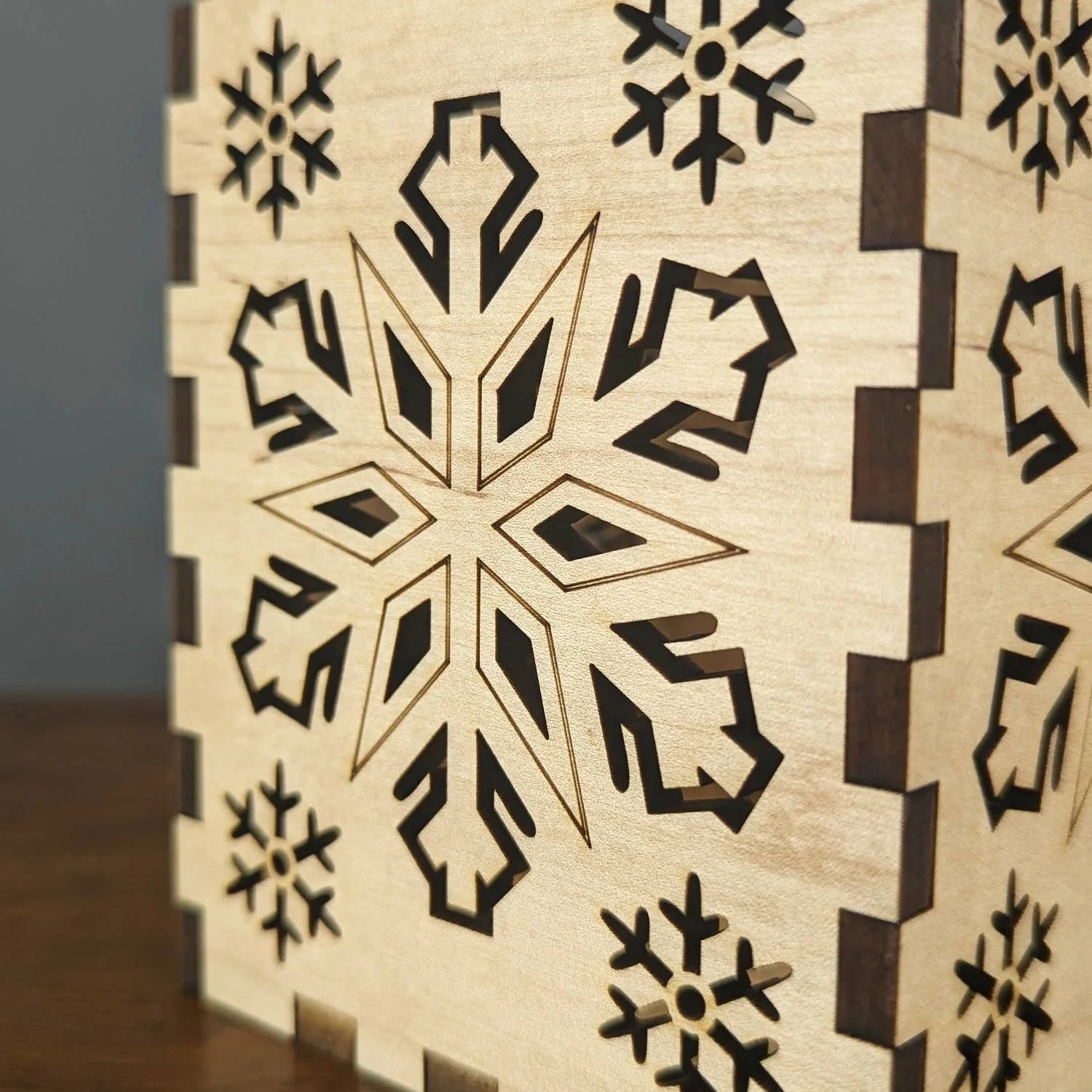 Close-up of laser-cut snowflake detail in solid maple wood.
