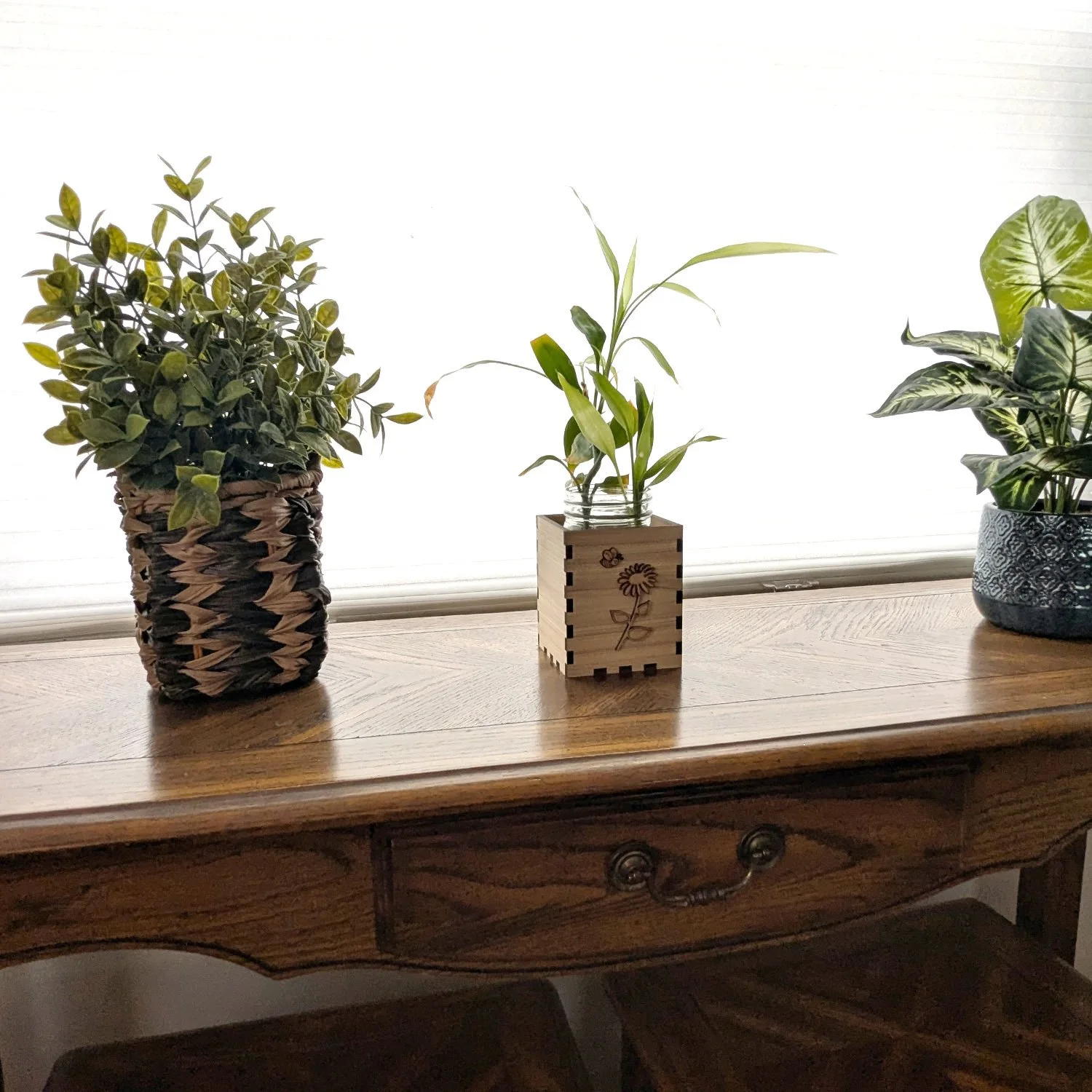 Handmade wooden vase box centerpiece with mason jar and plant, placed on a wooden table with decorative plants.