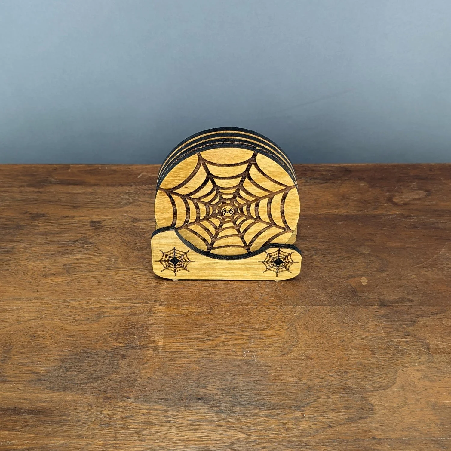 Complete Webworks Collection Set One stored neatly in the engraved wooden holder, showing four spiderweb coasters.
