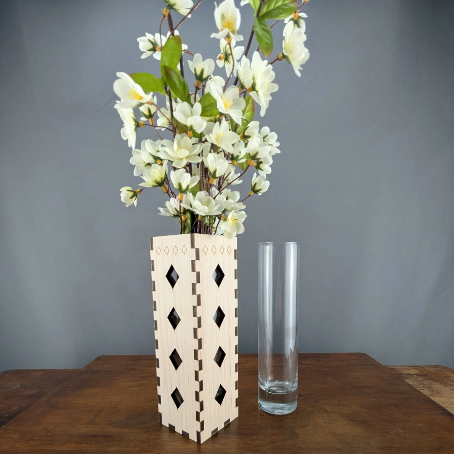 Side view of maple vase sleeve and removable glass insert, holding tall white flowers.
