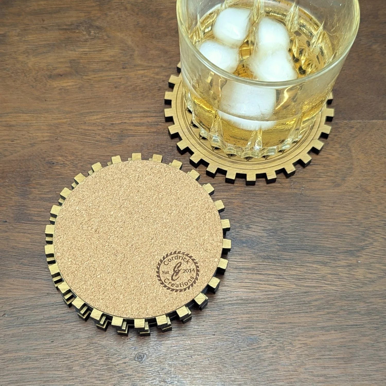 The cork backing of a gear-shaped wooden coaster, stamped with the Cordrick Creations logo.