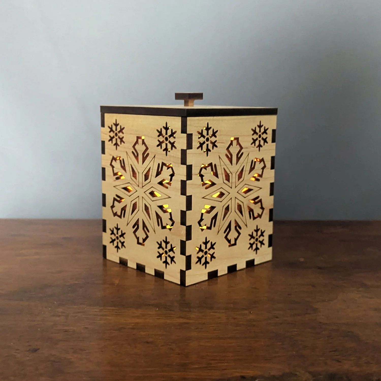 Angled view of the Maple Snowflake Lantern glowing with warm LED candlelight.