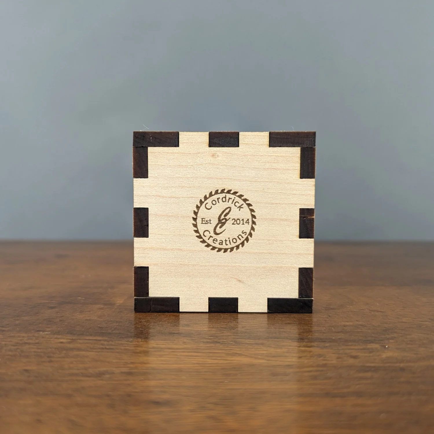 Bottom view of maple wooden vase sleeve featuring engraved Cordrick Creations logo with saw blade border.