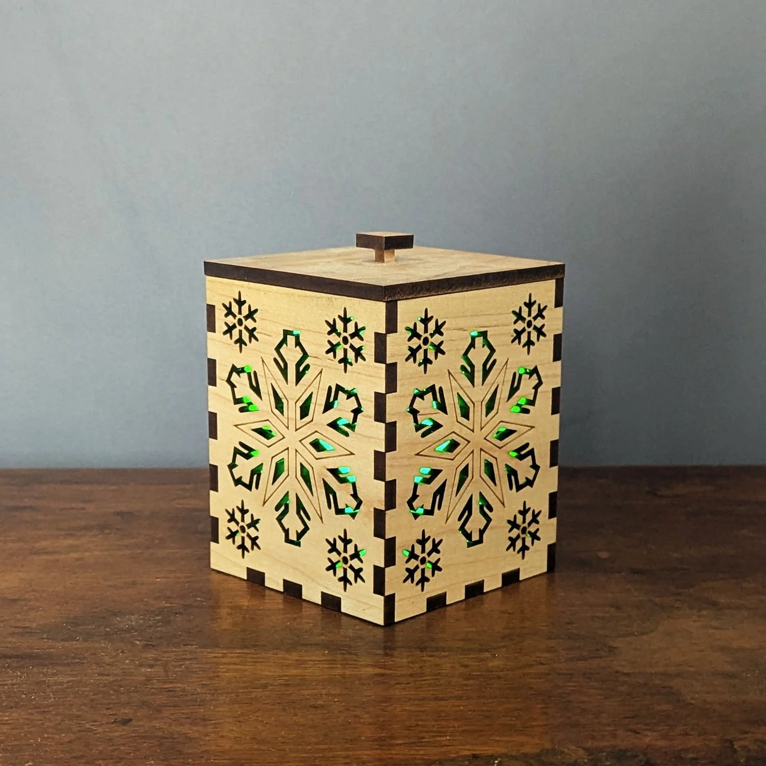 Maple Snowflake Lantern glowing green from an angle, showing laser-cut snowflake panels.
