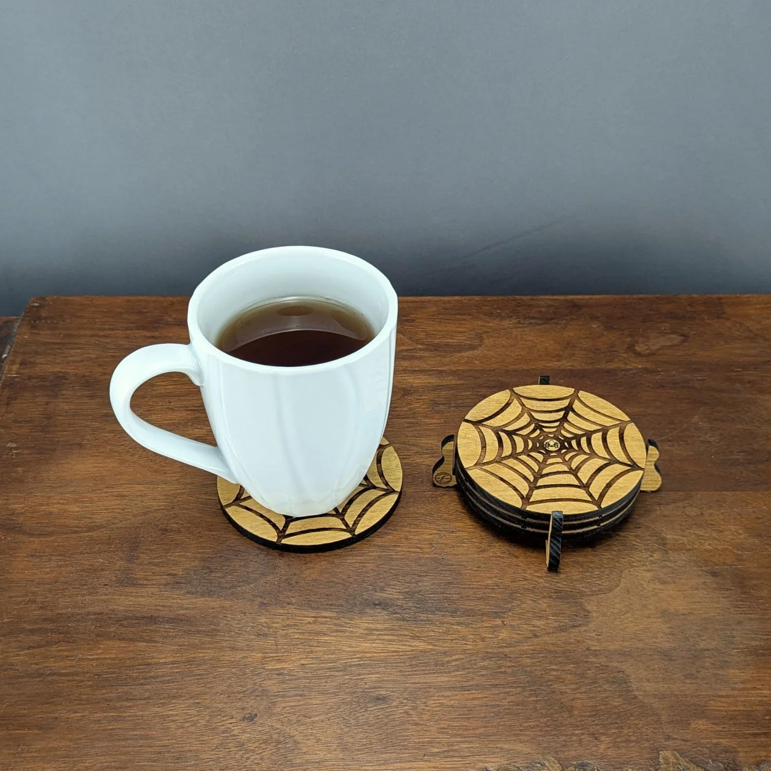 White mug on Shadow Web Coaster with coaster set in holder beside it