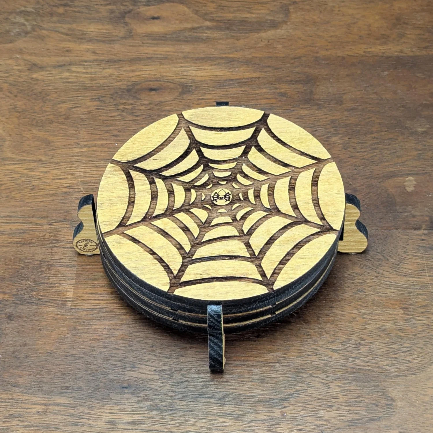 Stack of Shadow Web Coasters neatly placed in wooden holder on table