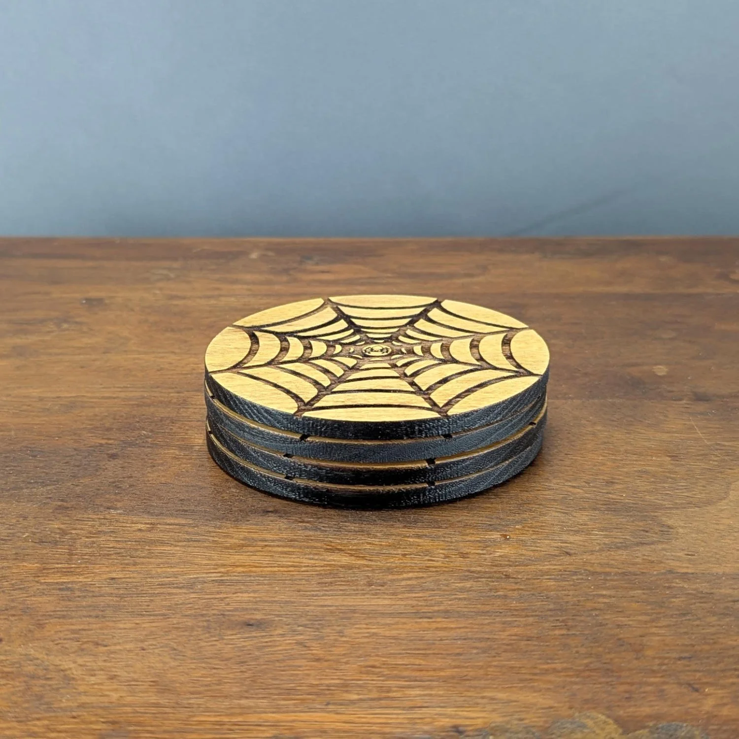 Side view of stacked Shadow Web Coasters showing black edges and slim profile