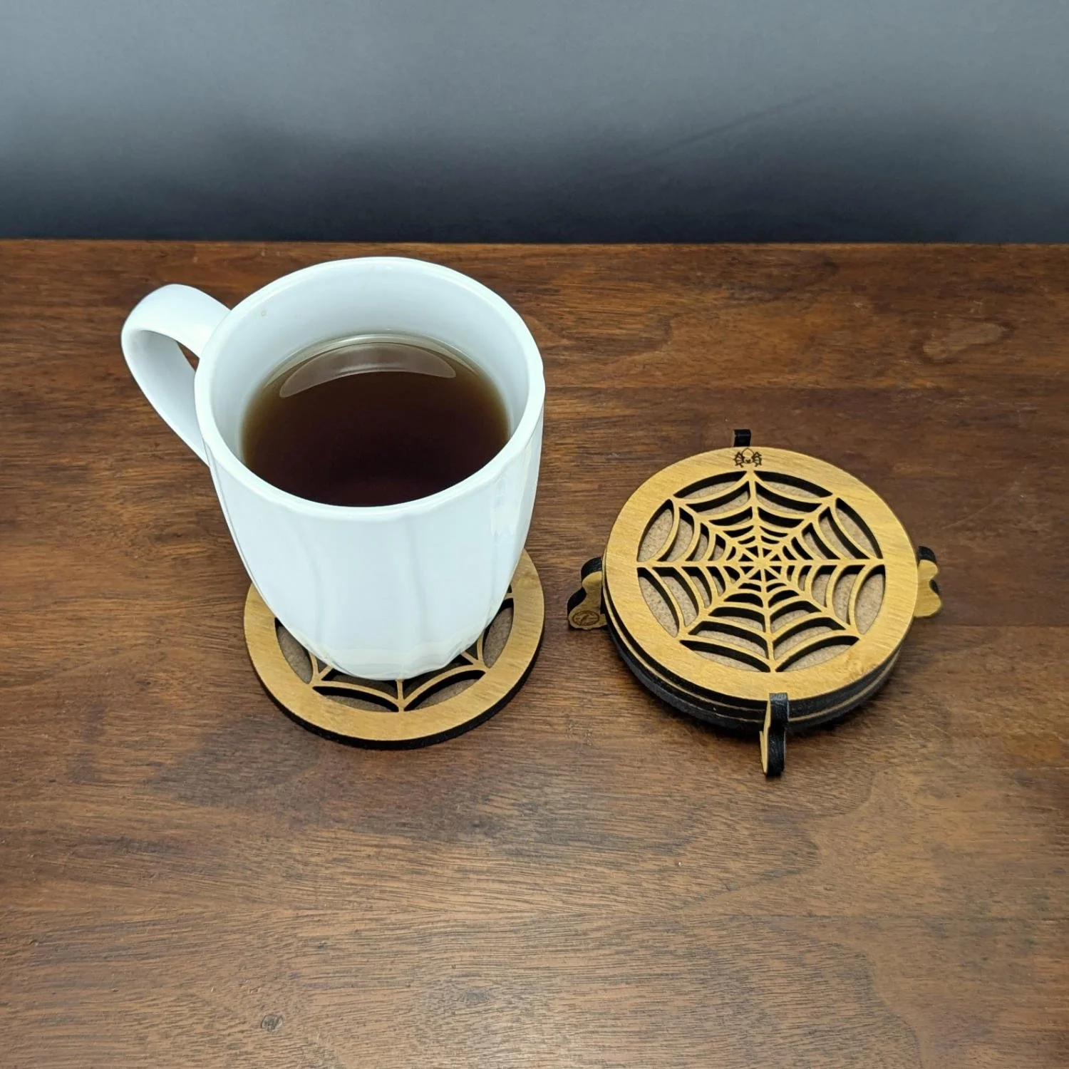 Phantom Web Coaster in holder next to mug of tea on wooden surface