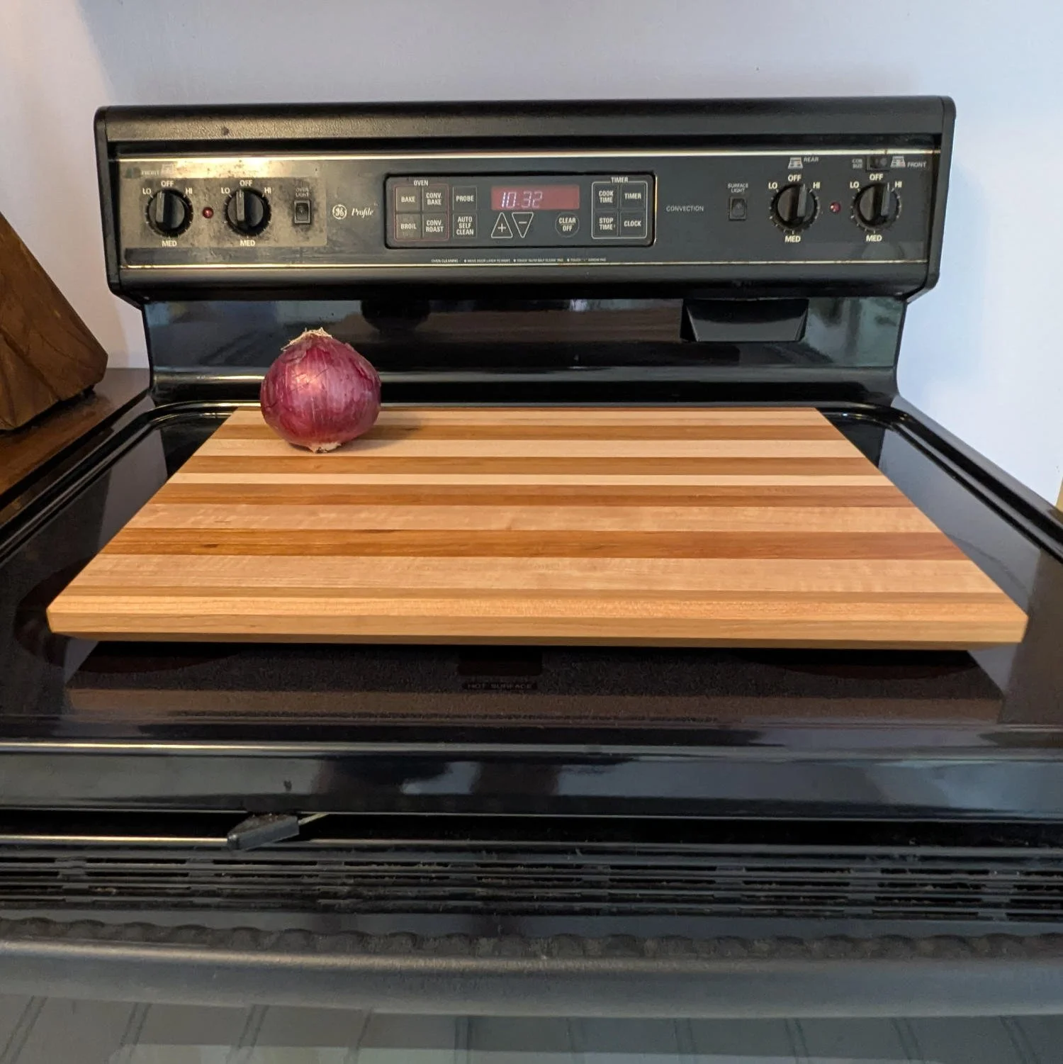 Maple and cherry cutting board on stovetop with onion