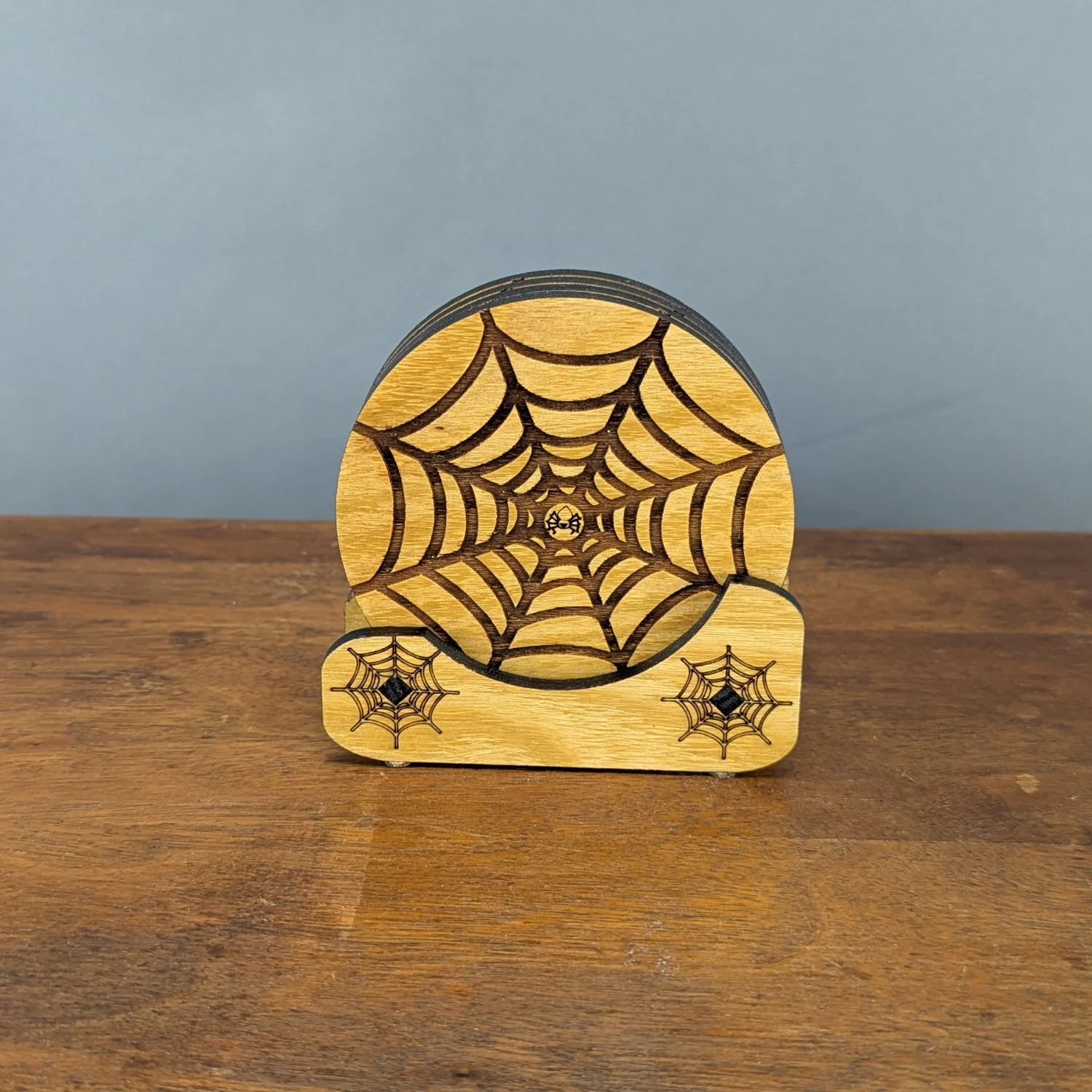 Shadow Web Coaster displayed in matching wooden Webworks Coaster Holder with engraved spiderweb design