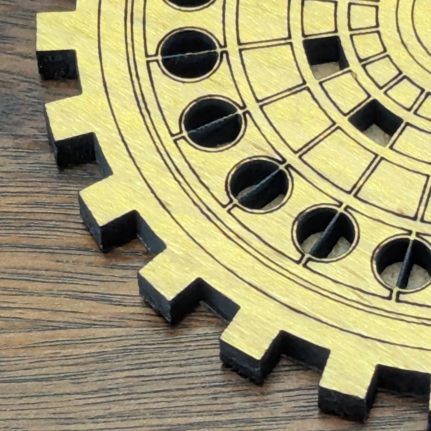 Close-up detail of the edge and cutout pattern of a wooden gear-shaped coaster on a table