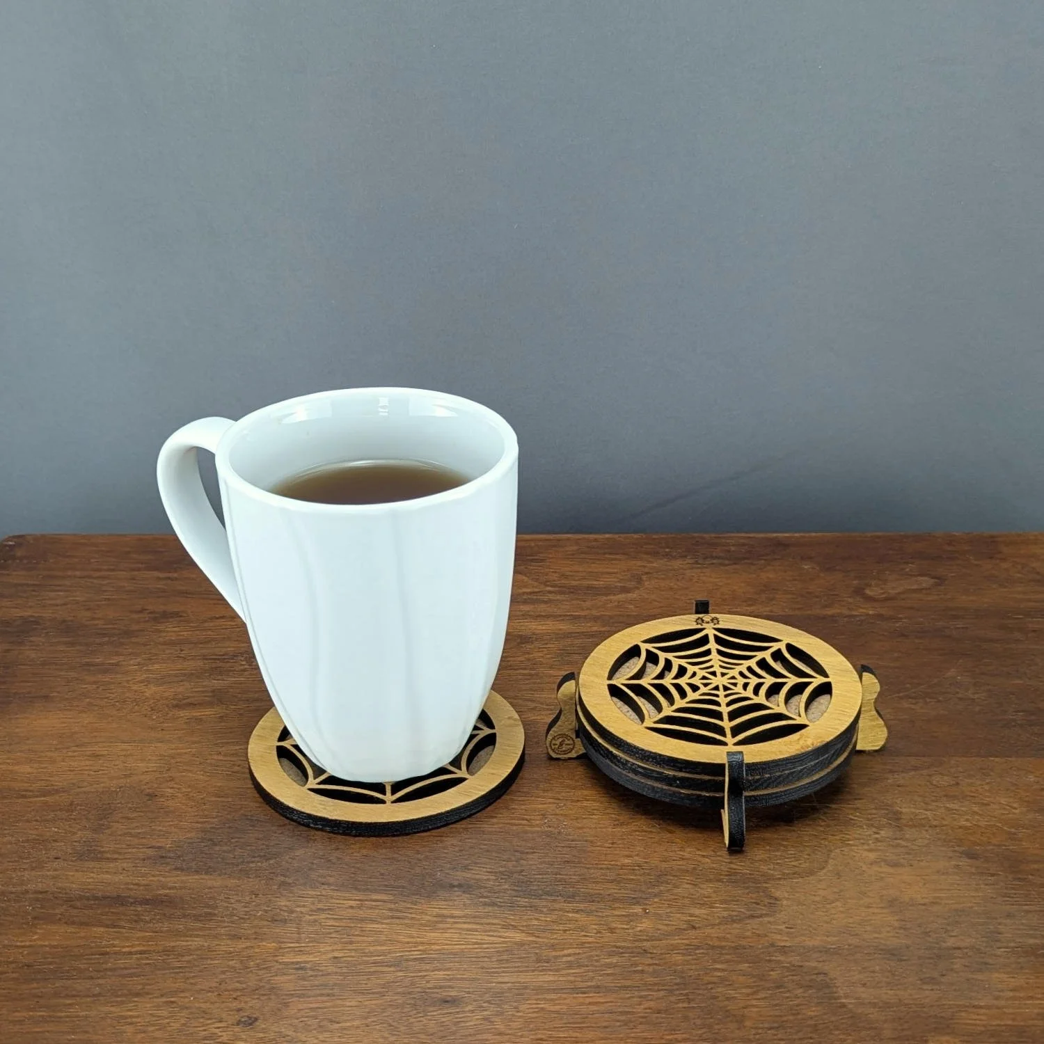 Phantom Web Coaster set with mug of tea and holder on wooden surface