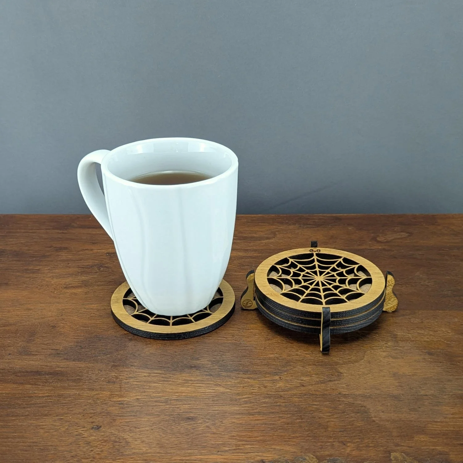 White mug of tea on Lace Web coaster with matching stack in holder beside it.