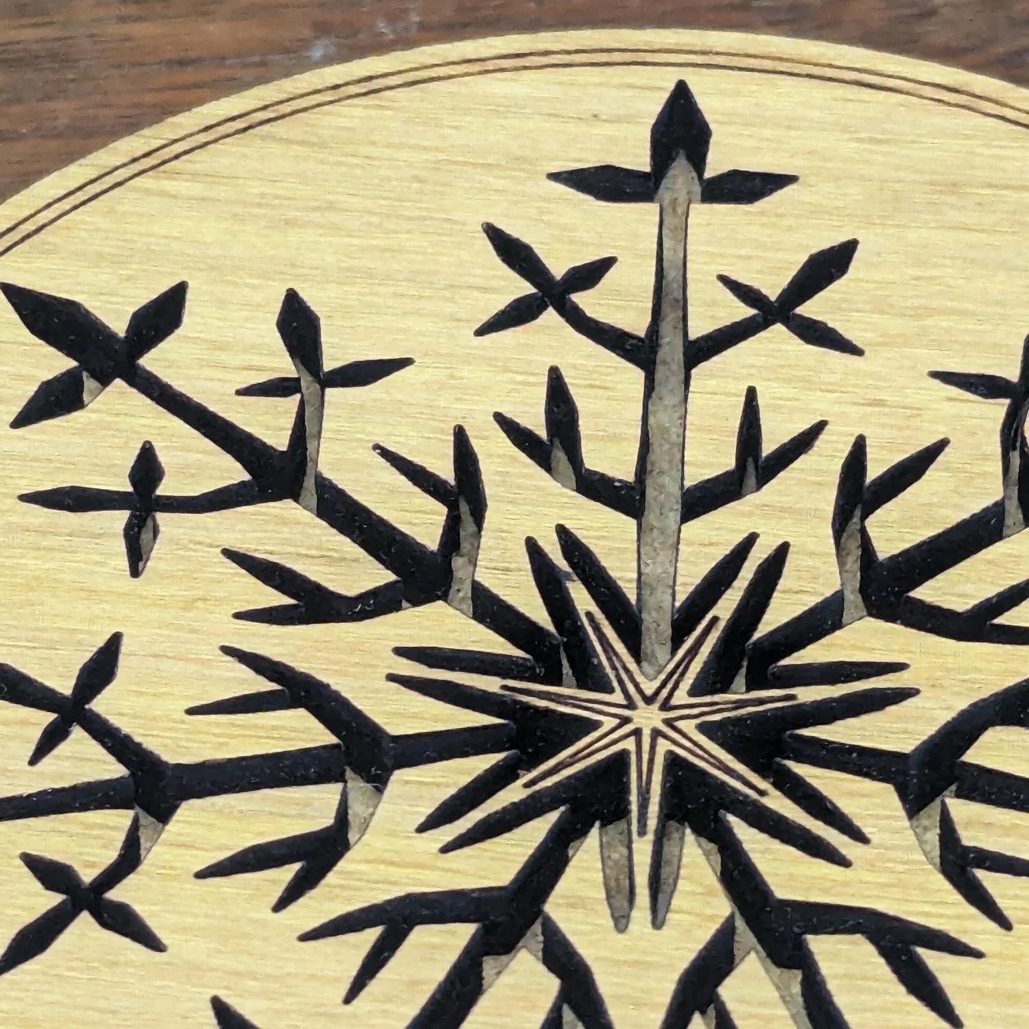 Macro detail of the center of a Black Locust snowflake coaster highlighting the intricate laser-cut engraving.