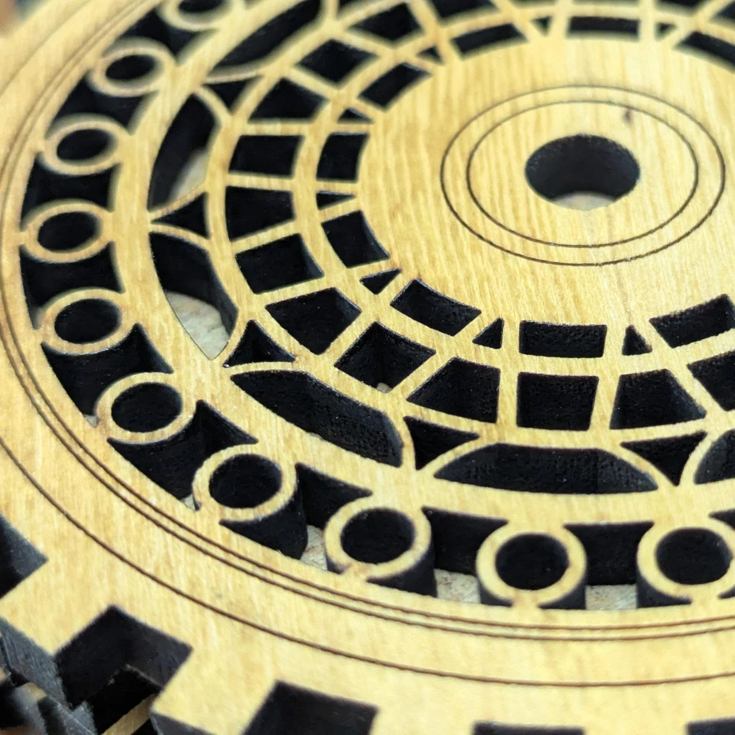 Detailed close-up of The Precisionist wooden coaster showing precise laser-cut geometric and circular gear pattern.