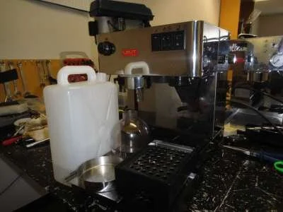 We start by removing all the loose bits from the machine. Take any beans out of the hopper, note the hopper setting then pull it straight up to remove it. Then take out the tank, lid and drip trays.