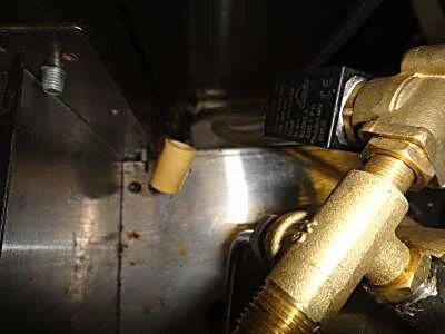 The final hose is the outlet of the solenoid 3-way valve that goes down into the drip tray. Lift up the boiler about 3 cm then gently work the rubber fitting off, using the pliers to grasp it.
