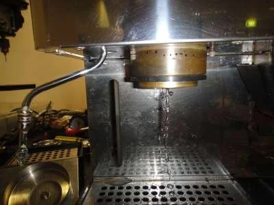 With the element still not connected, fill the boiler and check for leaks. Turn on the "Hot Water" switch with the steam wand closed for maximum operating pressure. If there are no leaks, refit the group collar and showerscreen, then reconnect the element. Once the machine has heated, detergent backflush. After backflushing, replace the indicator lamp and button up the machine.