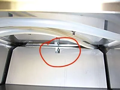 Looking down into the tank area, a screw is visible in the cutout slot.  Unscrew this a couple of turns, then slide off the rear panel.