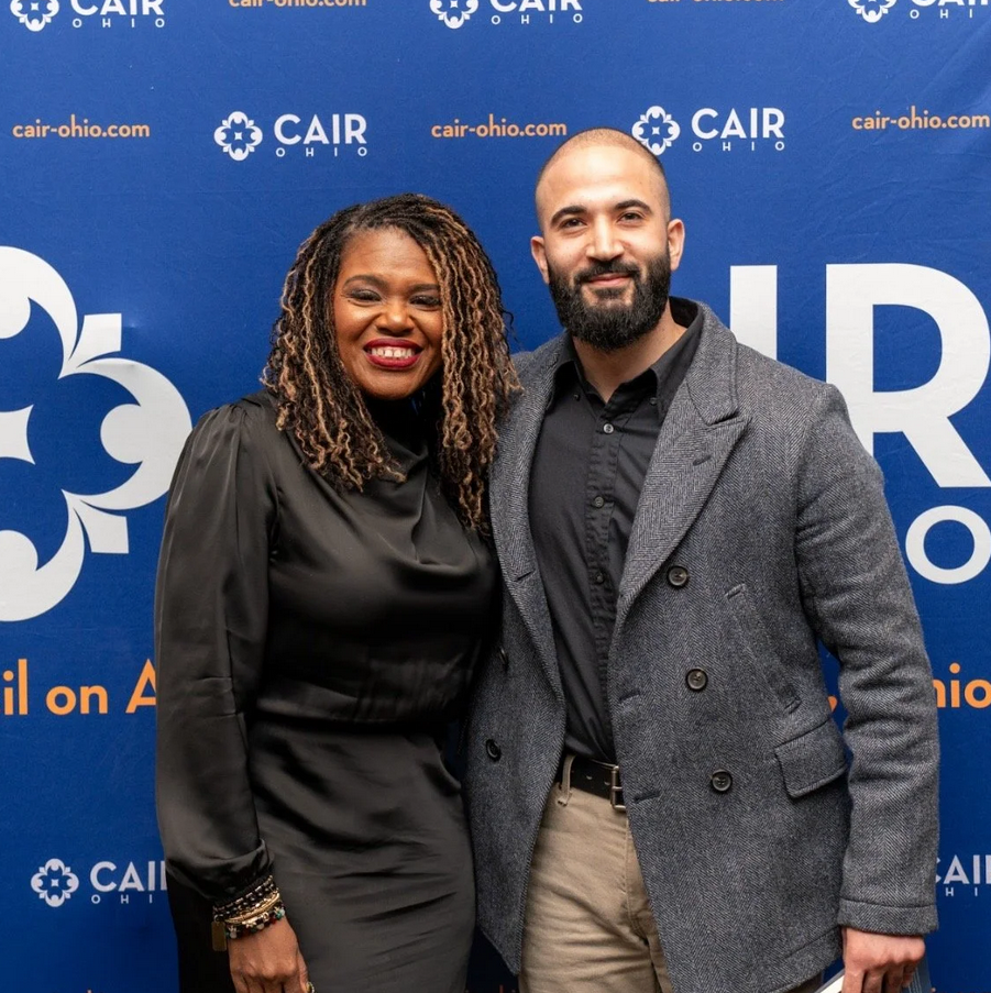 Two people standing in front of a blue backdrop with 
