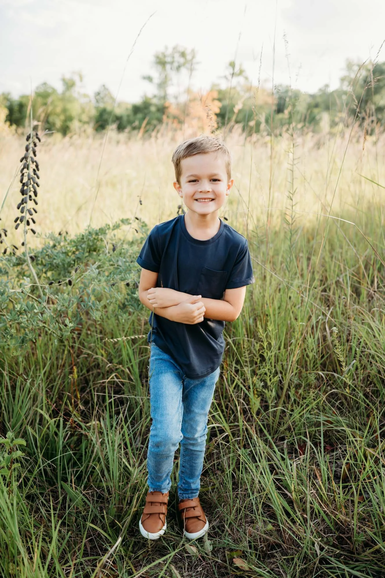 little boy in green field smiling at Noblesville family photoshoot