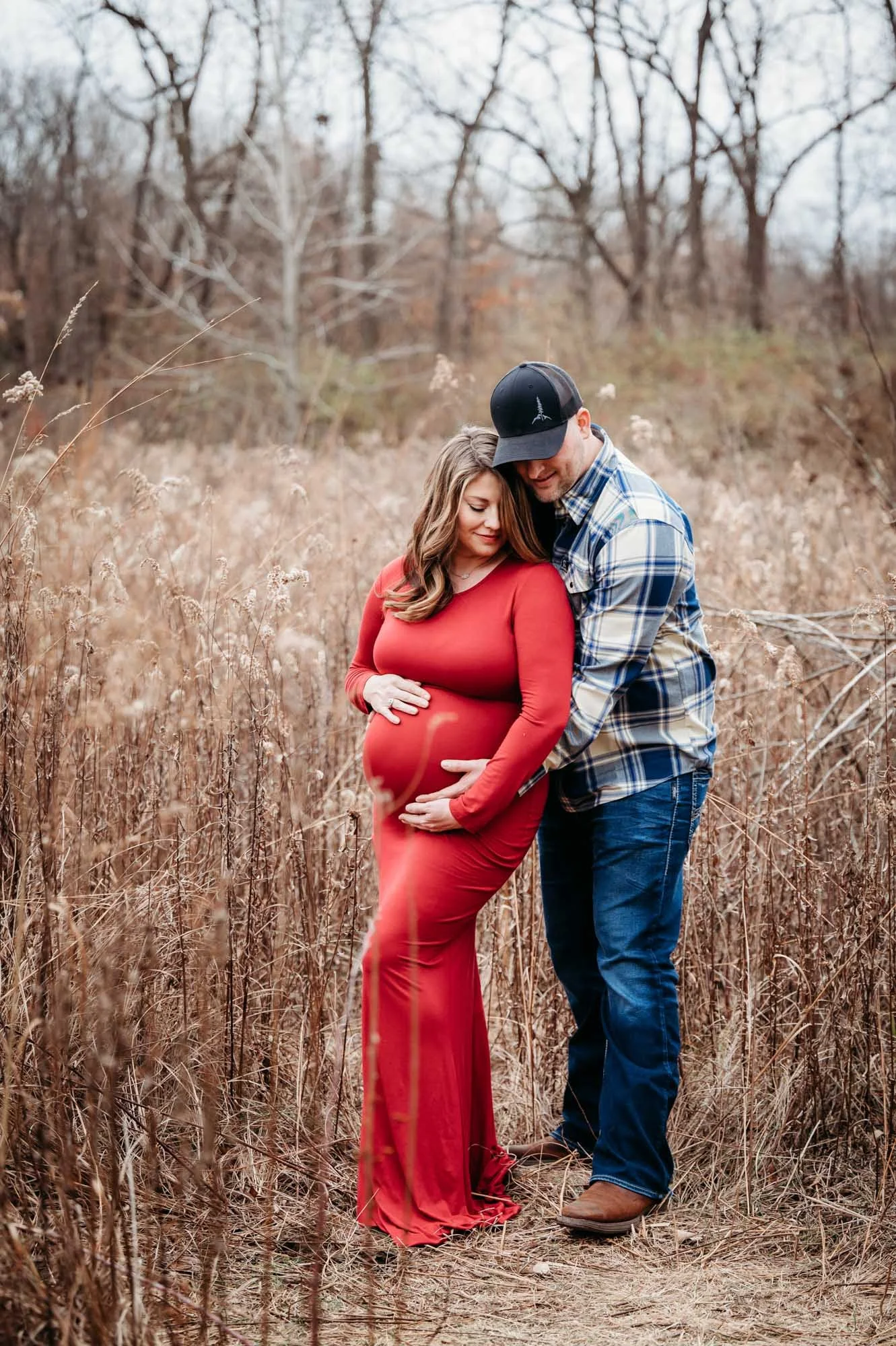 expecting couple hugging in natural field setting during Westfield, Indiana maternity photoshoot