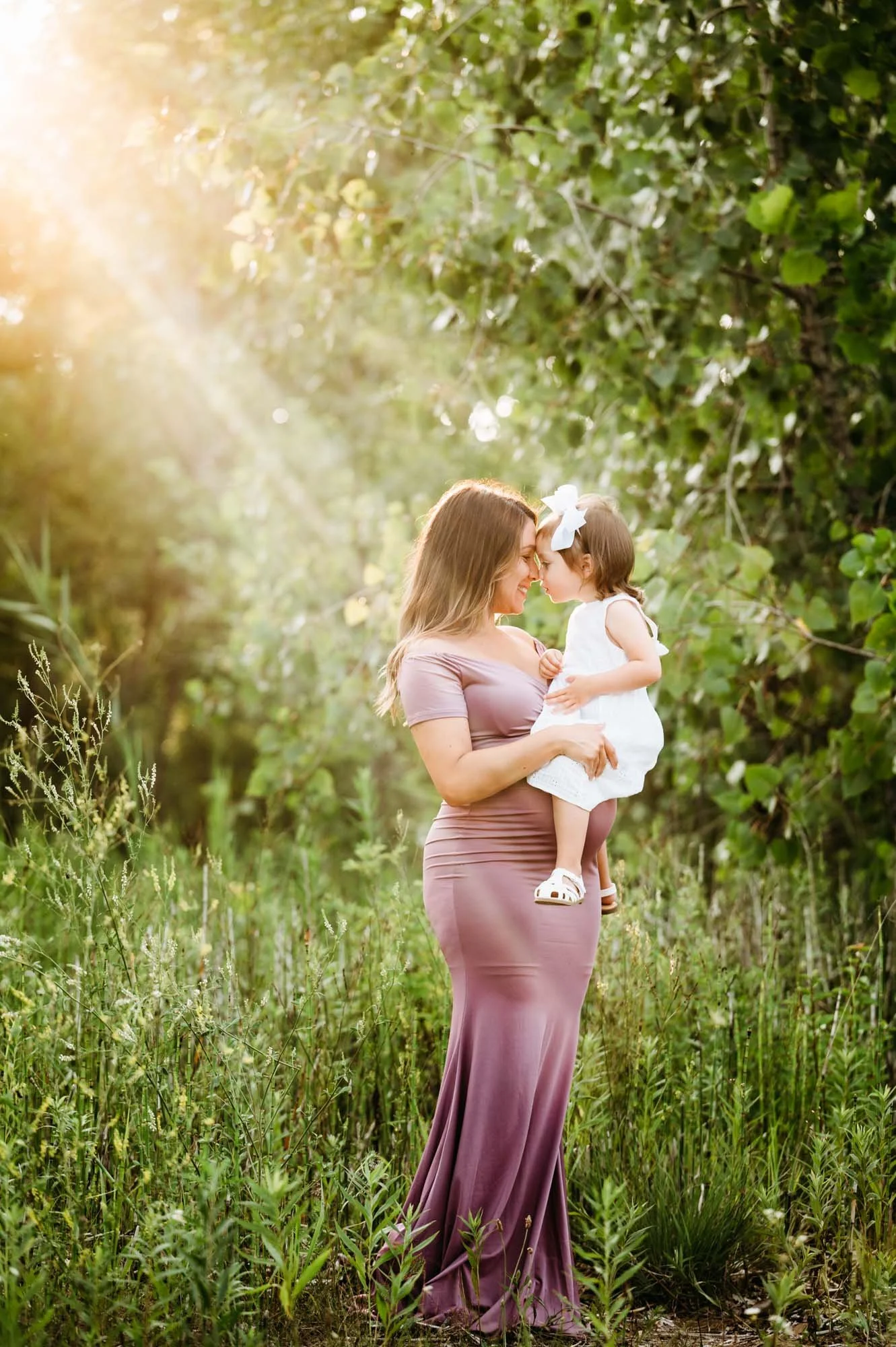 toddler resting up her pregnant mom's belly during maternity photoshoot in Carmel, IN