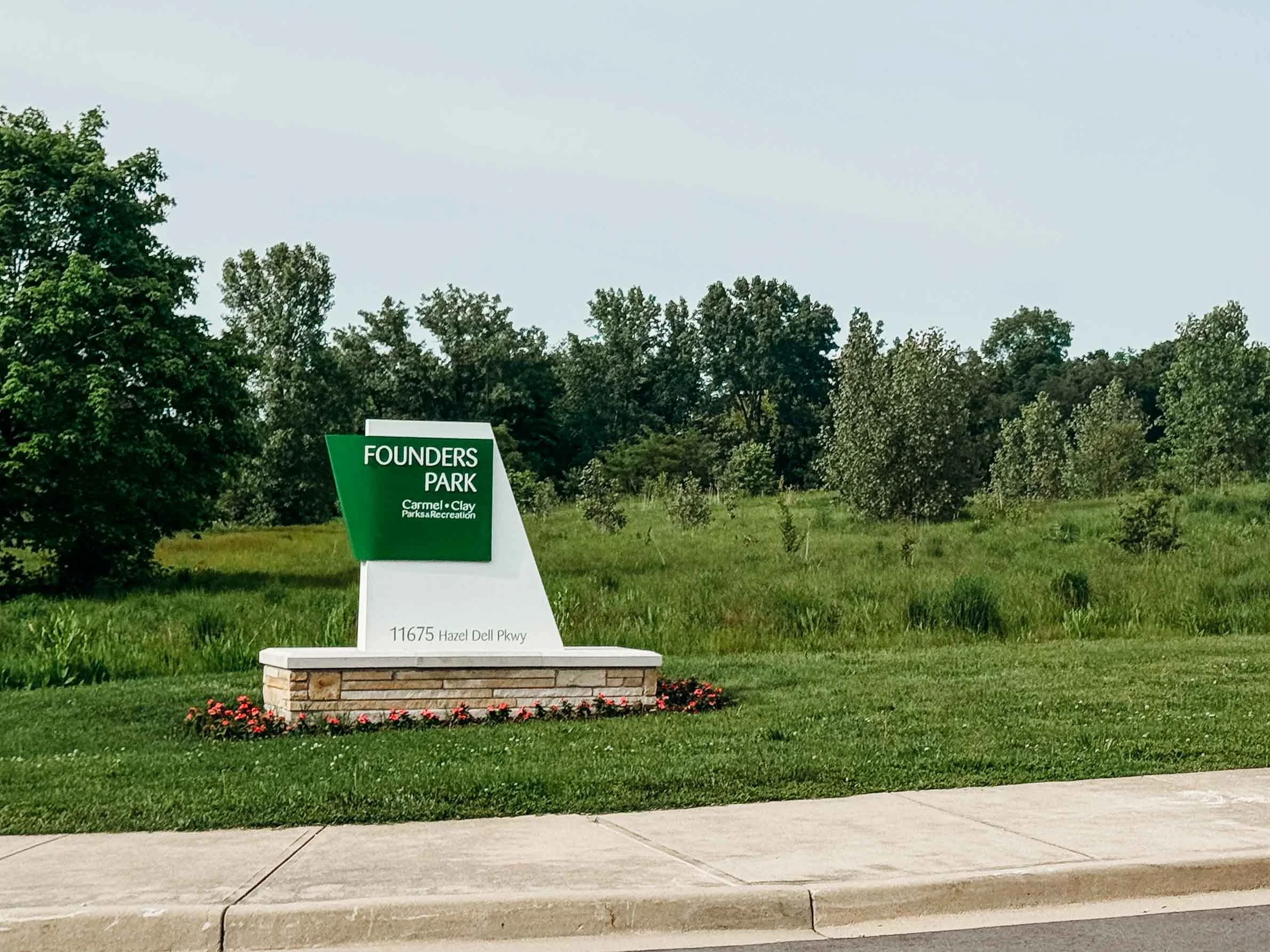Founders Park entrance sign with grassy fields and trees in Carmel, Indiana.