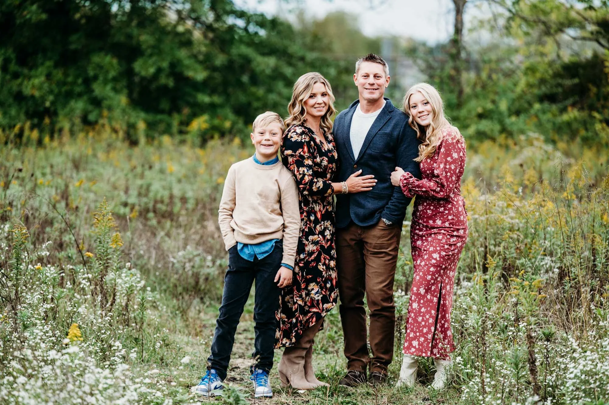 family of four standing together in a field of wildflowers in Carmel, Indiana during photoshoot