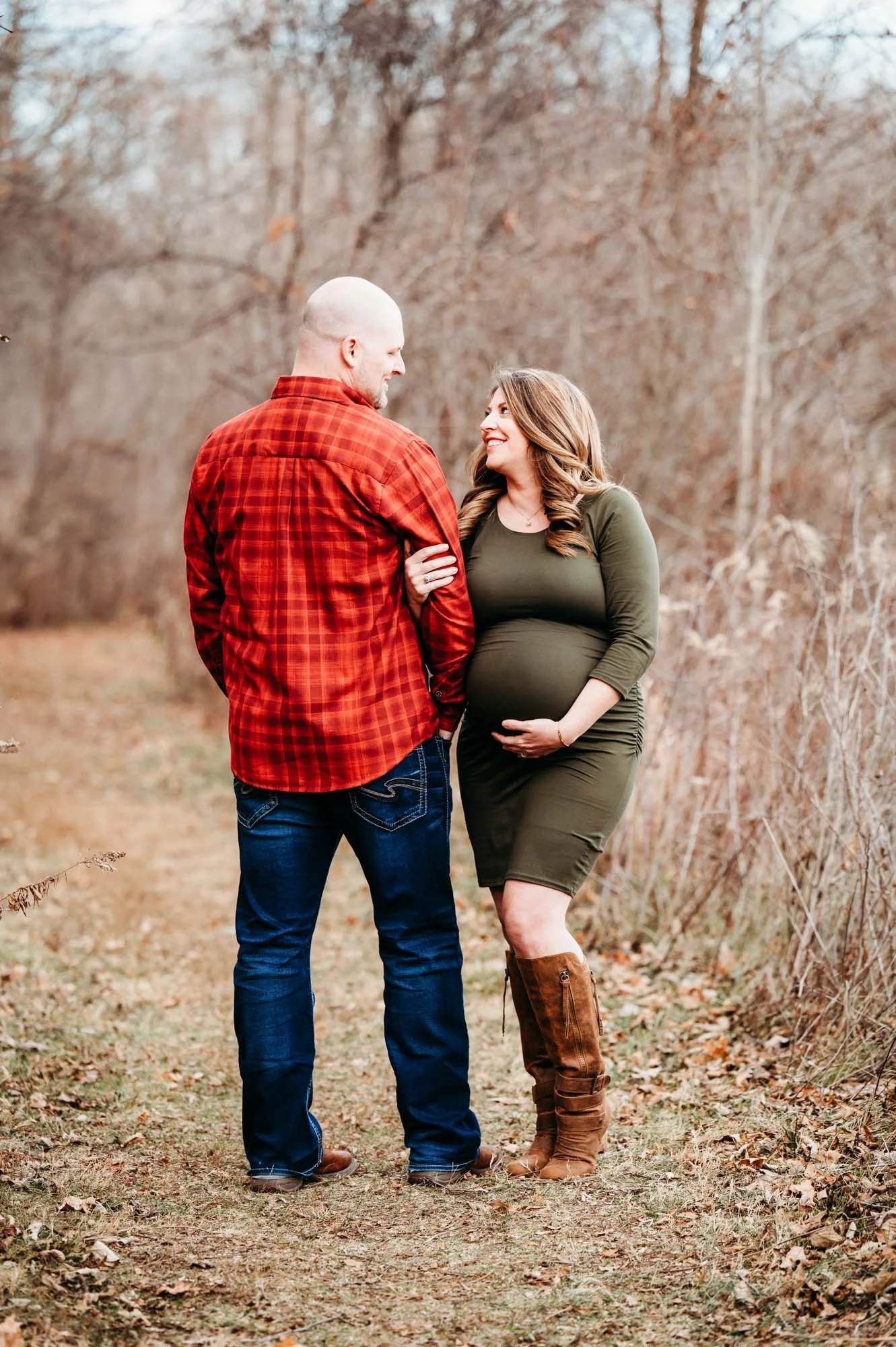expecting couple looking up at each other in natural field setting during Westfield maternity photoshoot