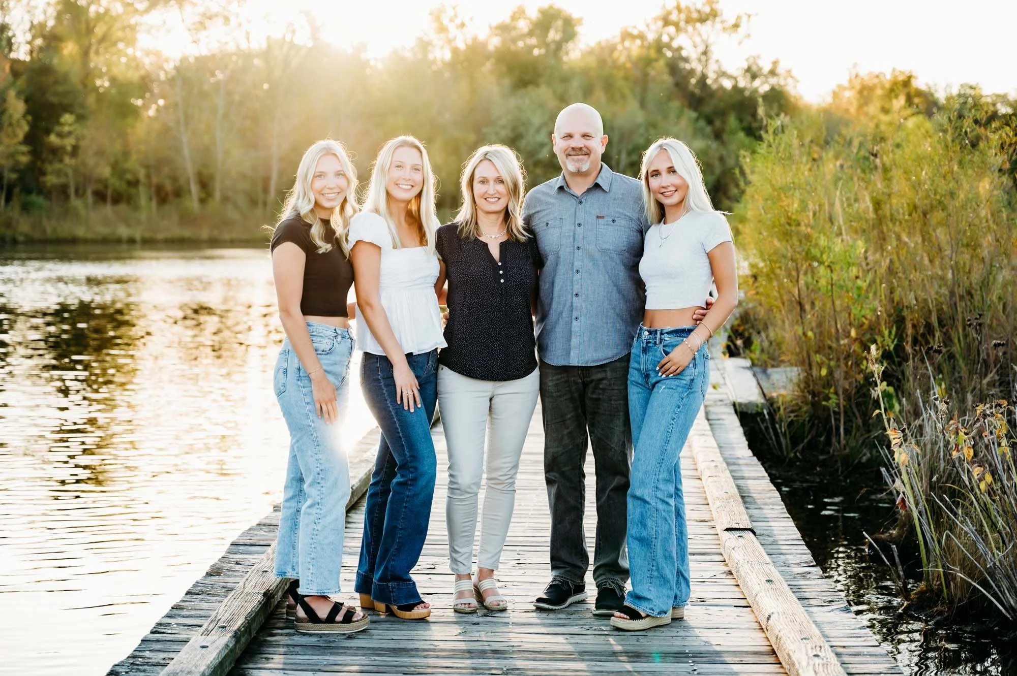 Family of five posing together on a dock by the water during an outdoor family session in Westfield, Indiana