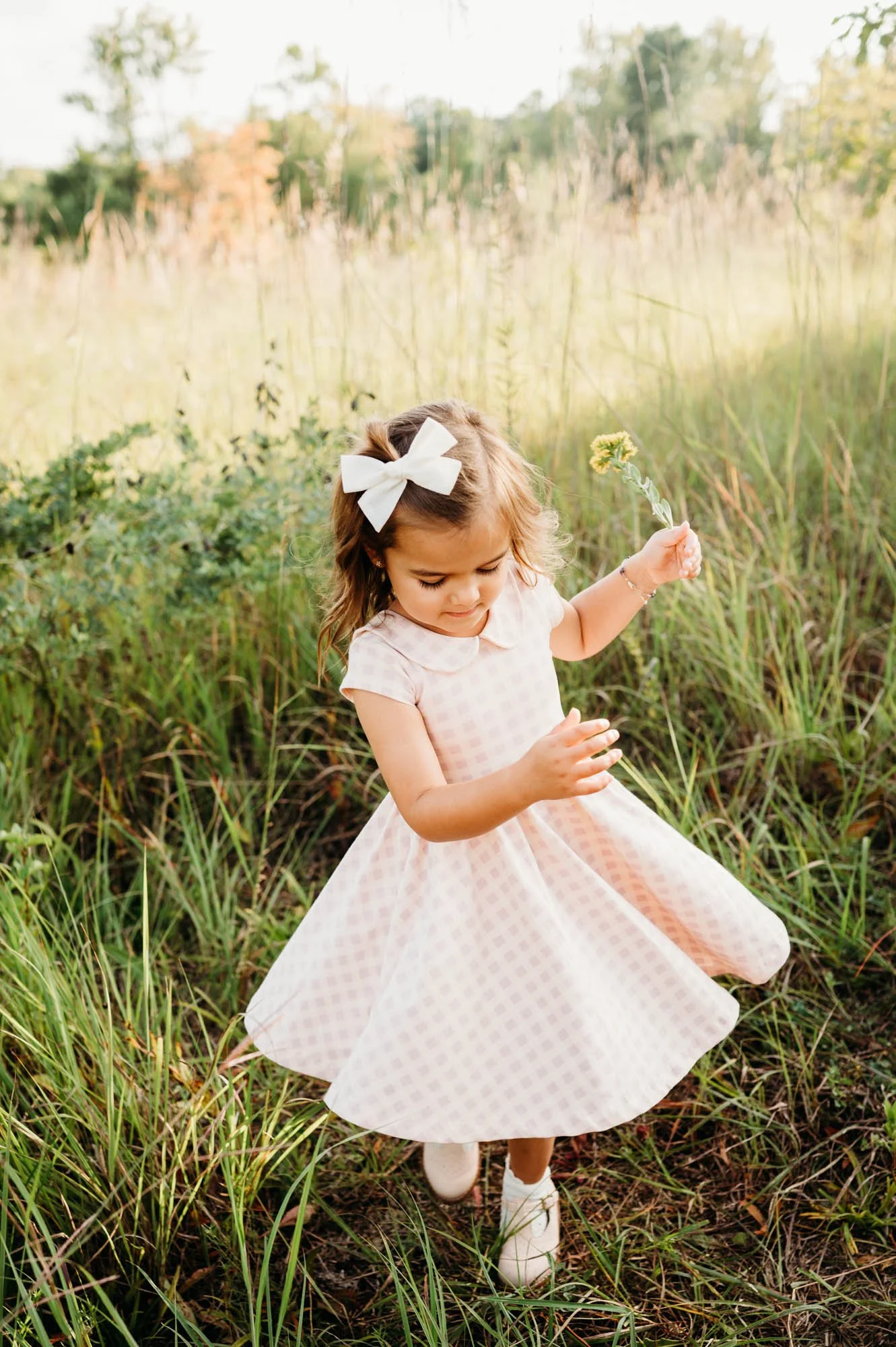 little girl twirling her dress in a field in a family photoshoot in Noblesville, IN