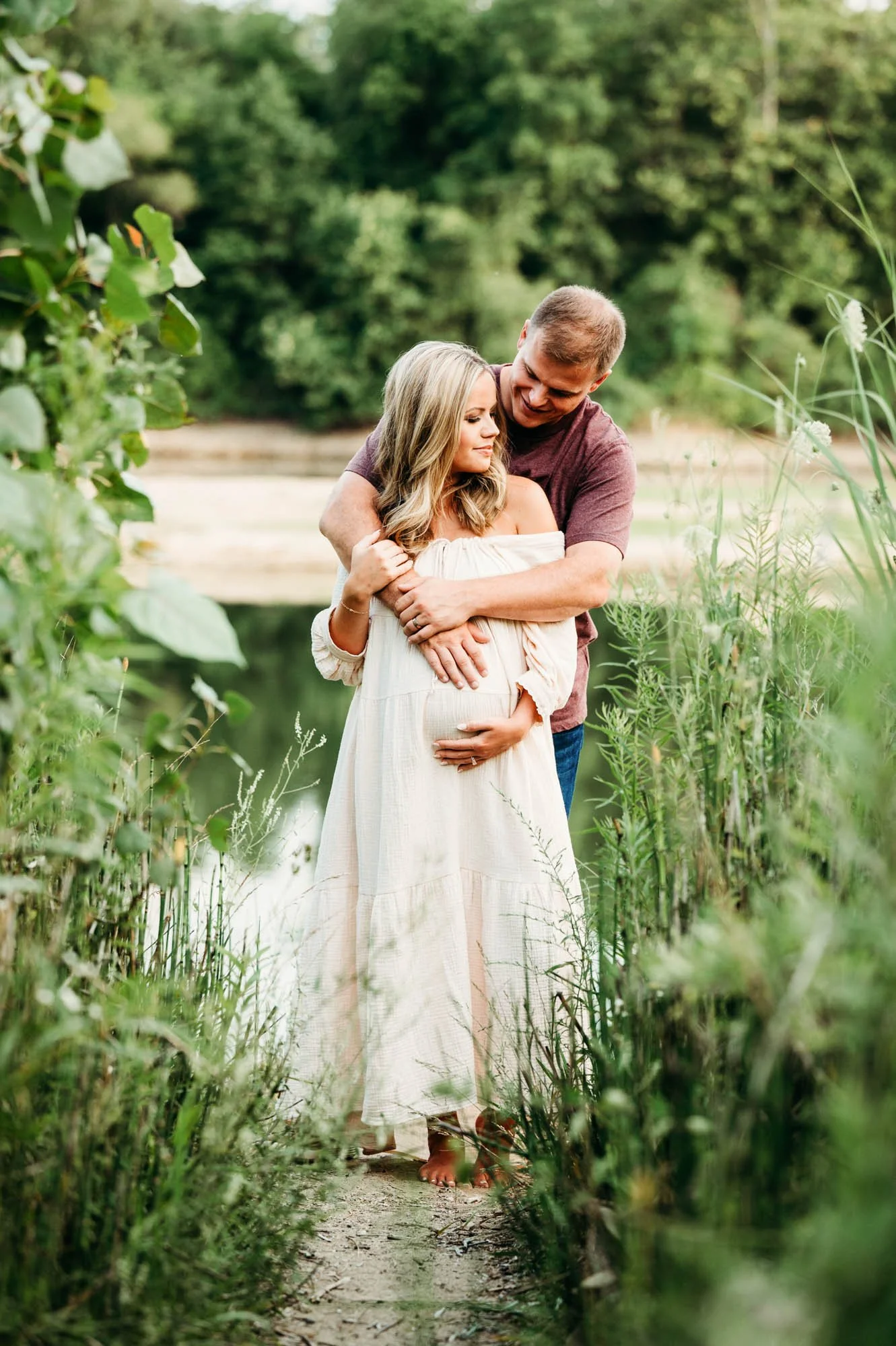 Expecting couple holding hands by the water during a maternity session at Ritchey Woods Nature Preserve in Fishers, Indiana.