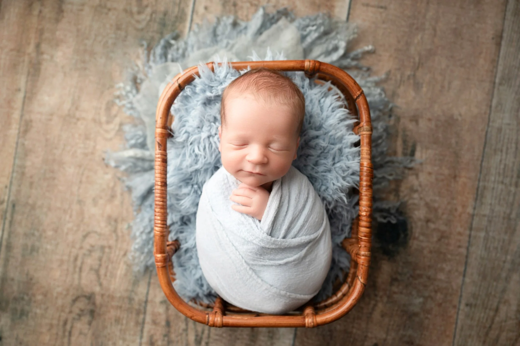 newborn baby in blue swaddle in prop