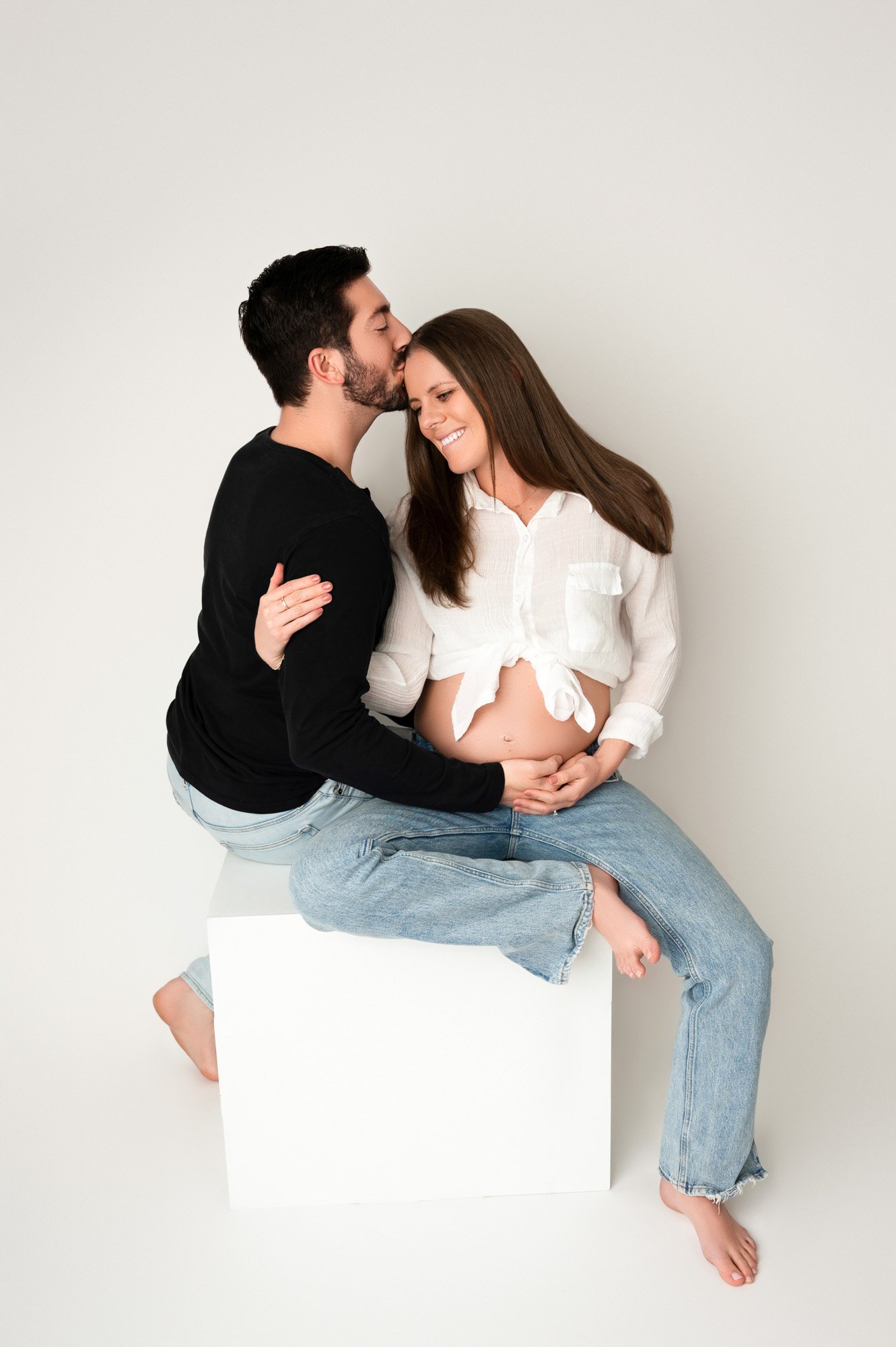 young couple expecting baby sitting on studio prop in Noblesville maternity photoshoot