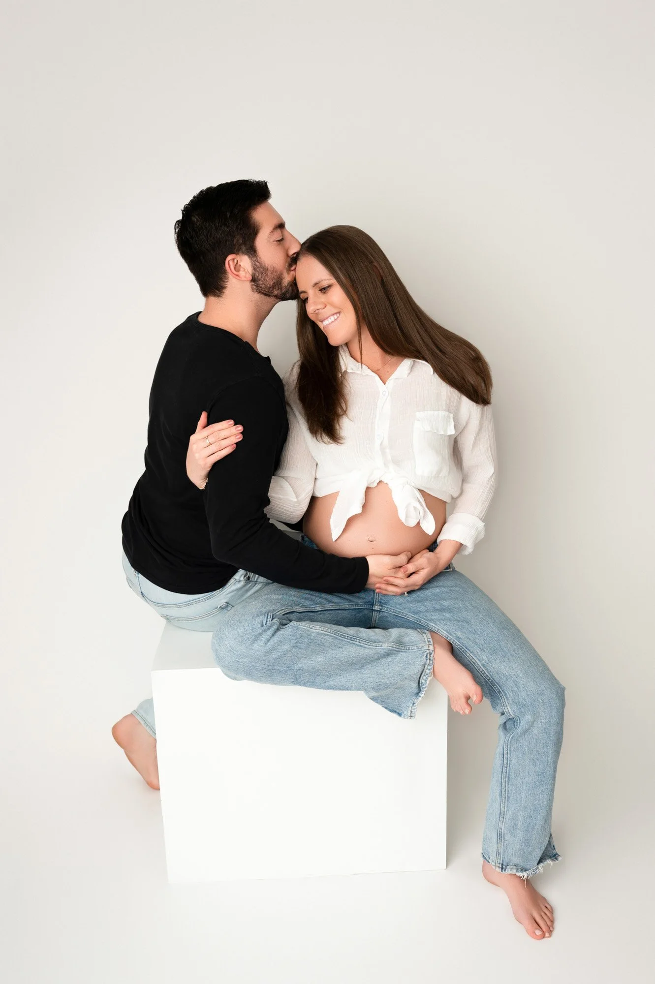 young couple expecting baby sitting on studio prop in noblesville maternity photoshoot