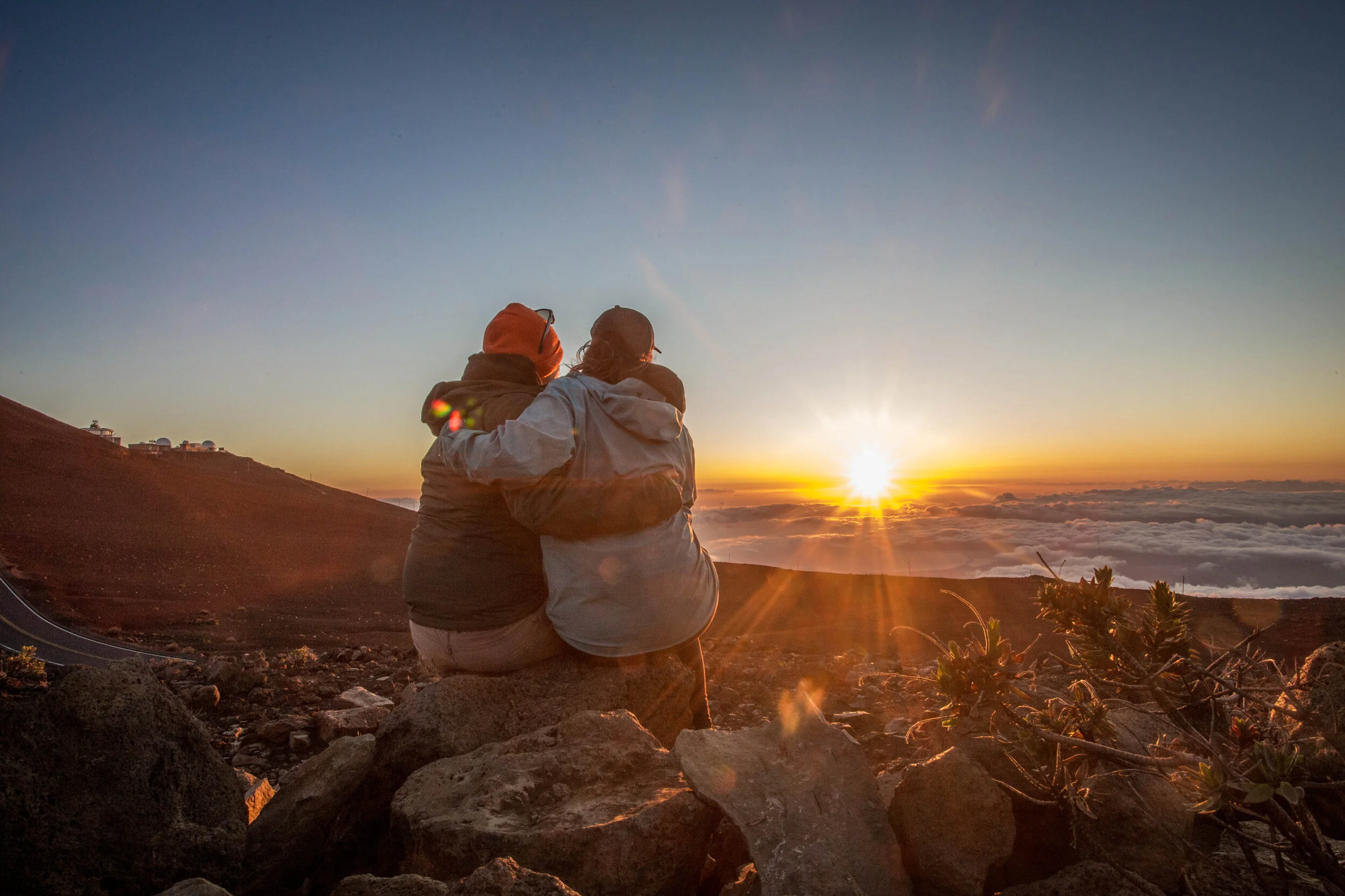 A top a mountain a couple looking at the sunny horizon