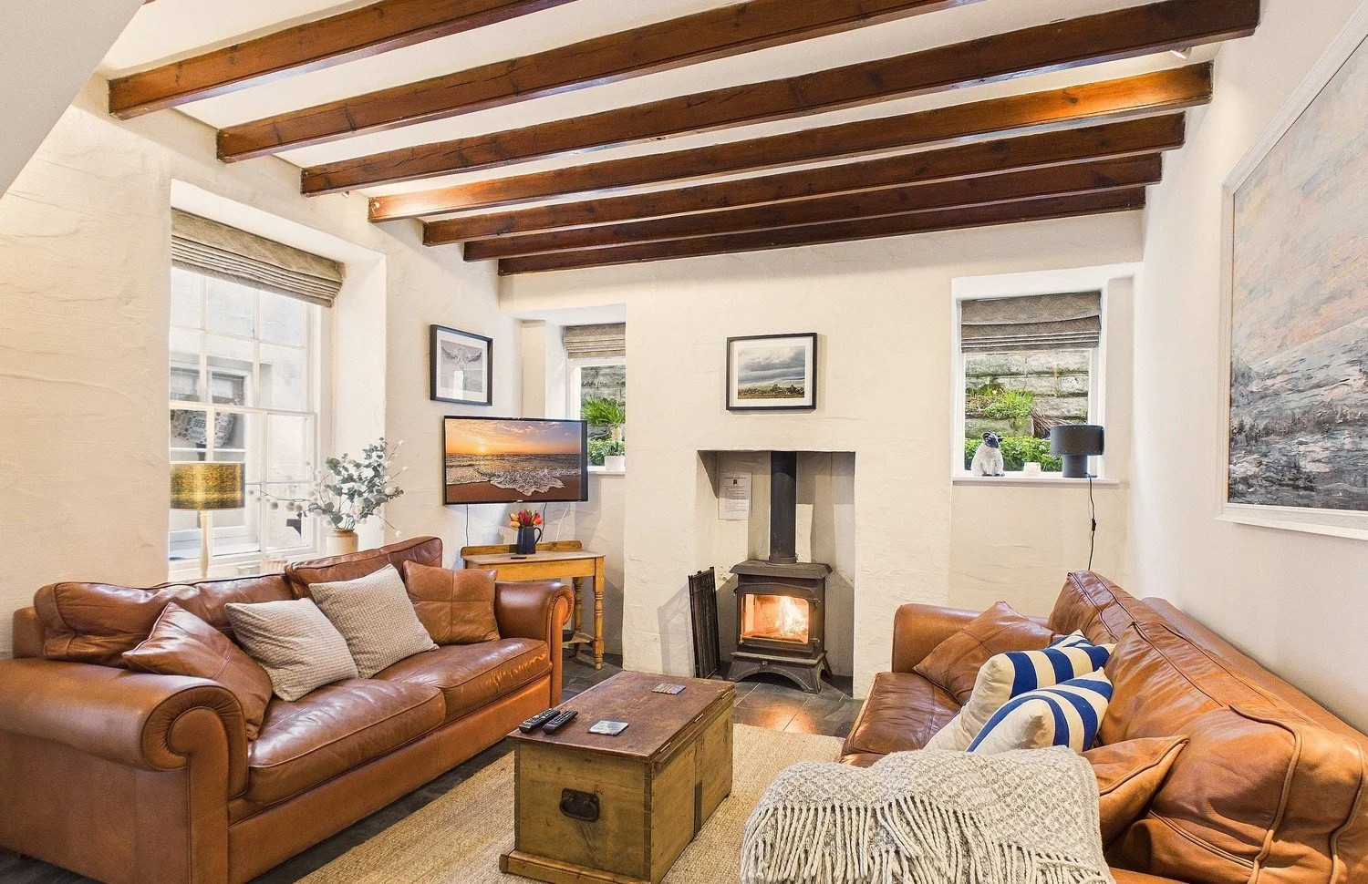 Lovely cosy living room with tan leather sofas, woodburning stove, soft furnishings and TV on wall - Newport, Pembrokeshire
