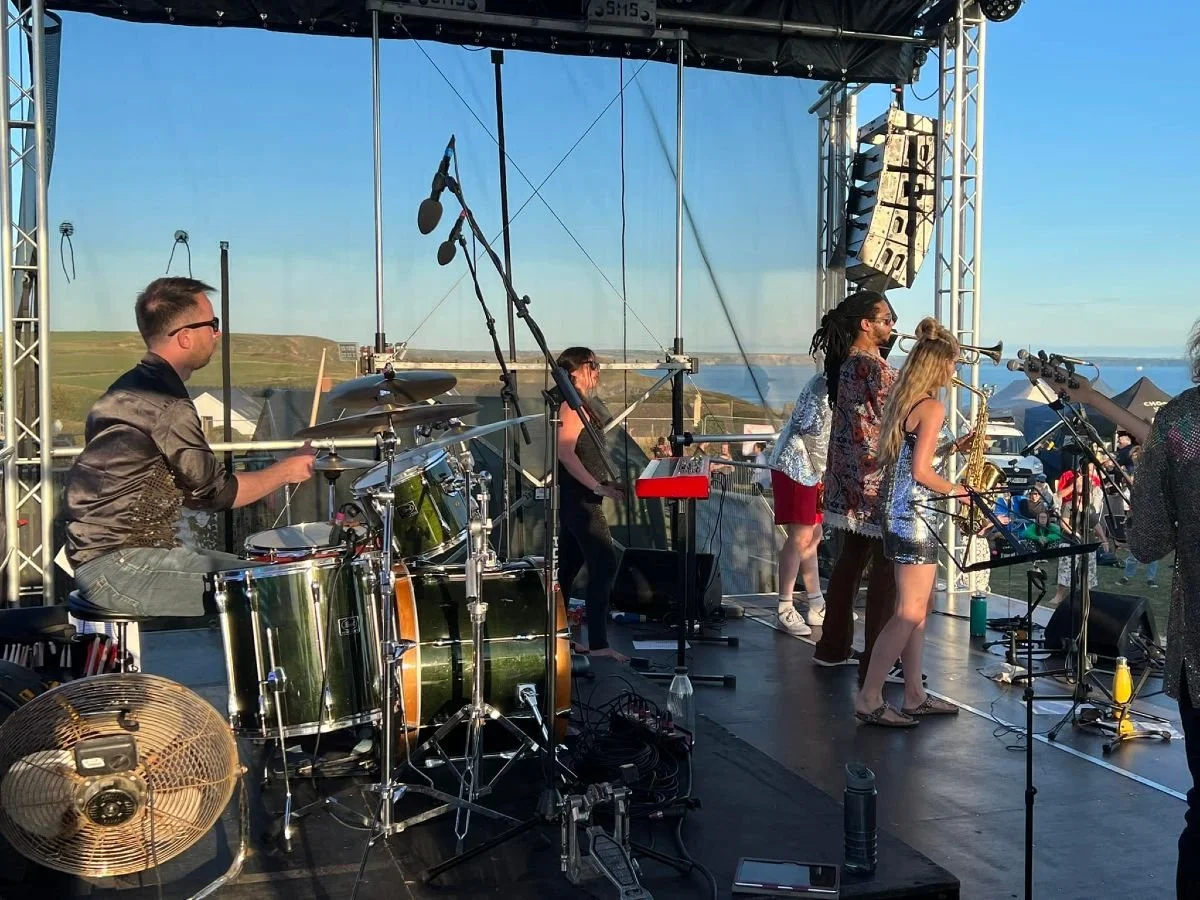 Edge Festival Solva band on stage with Pembrokeshire coastline and sea view behind