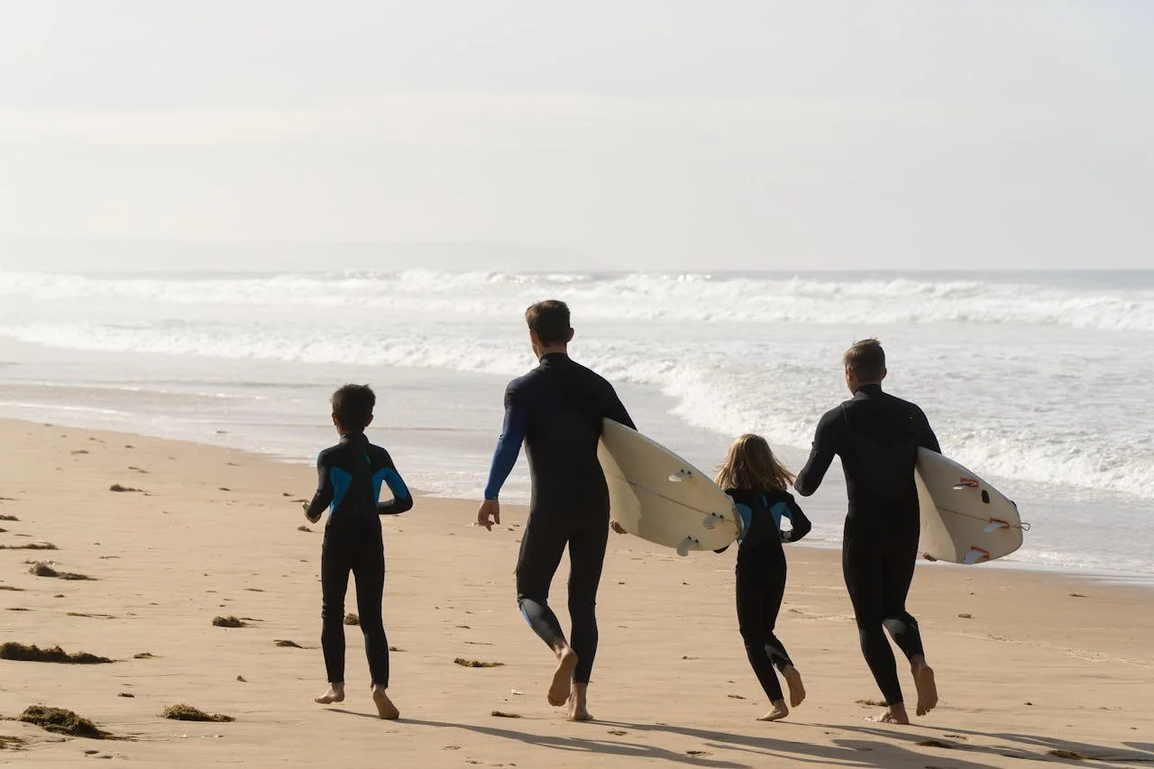 Family with surfboards under their arms on the beach