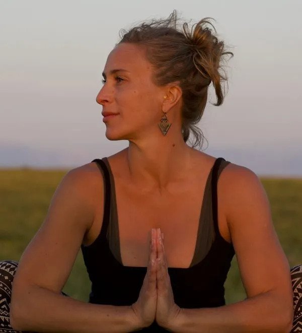 Woman in black tank top doing yoga with hands in prayer position, outdoors